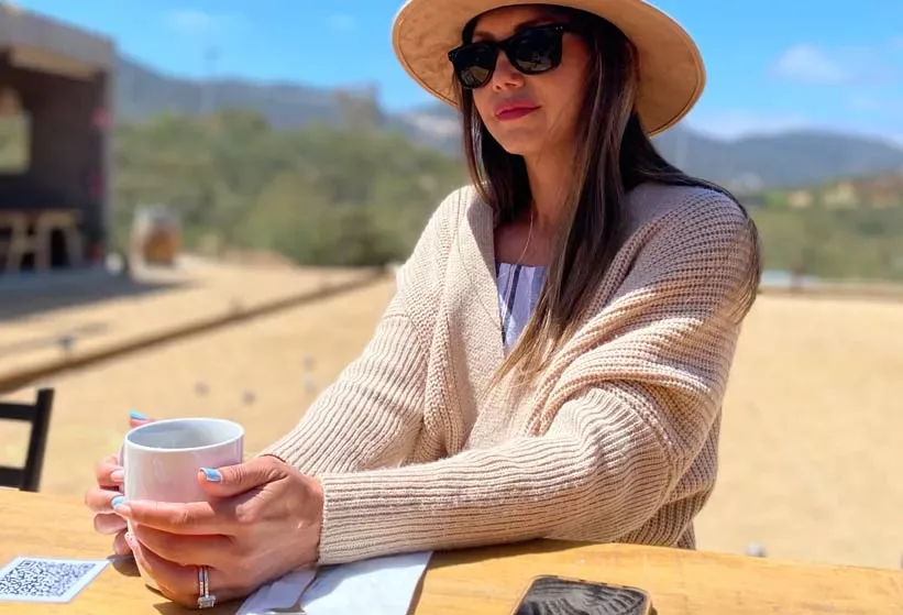Lucero Galiano con sombrero y taza de café, sentada al aire libre